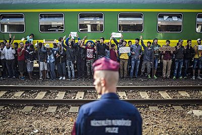 Un polica vigila mientras refugiados piden poder continuar su viaje rumbo a Europa Occidental en la estacin ferroviaria de Bicske (Hungra) el pasado 4 de septiembre.
