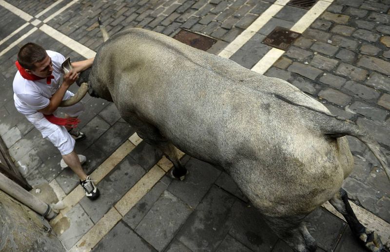 Un mozo se escabulle de los cuernos de un toro en el quinto encierro