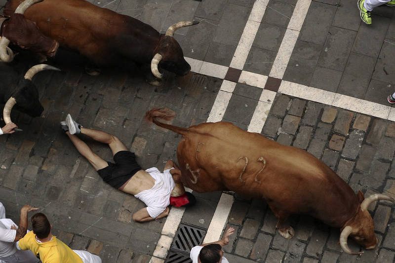 Los toros de la ganadería gaditada de Núñez del Cuvillo pasan por encima de un mozo en el tramo inicial de la calle Estafeta en el septimo encierro de los Sanfermines 2017