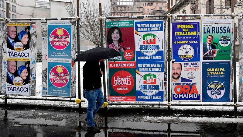 Un hombre pasa por delante de varios carteles electorales en Milán