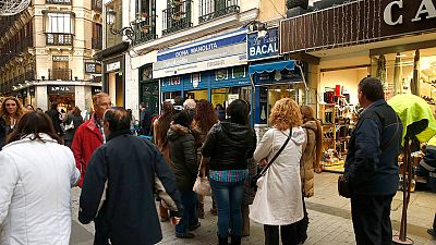 Varias personas guardan cola para comprar en Madrid décimos para el sorteo de Lotería de Navidad