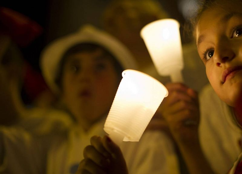 Un grupo de niños sujeta las tradicionales velas blancas para despedir la fiesta grande de Pamplona.