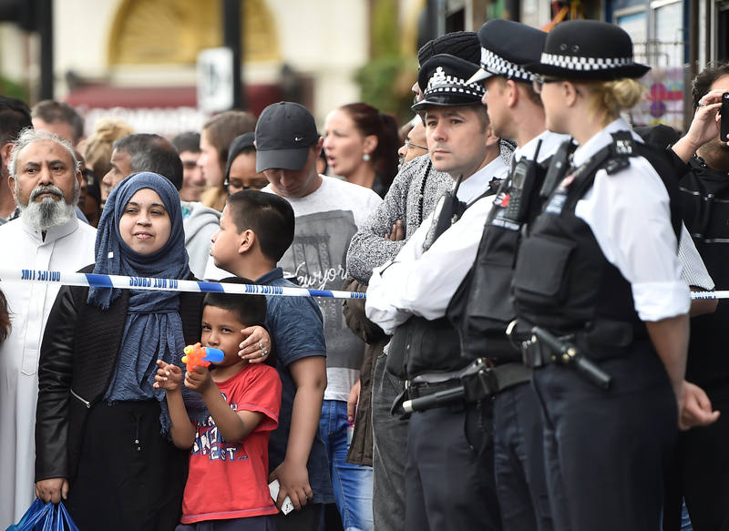 Un niño juega con una pistola de agua mientras la gente se arremolina tras el cordón policial en Barking Road, donde se ha producido una redada de la policía en el marco de la operación antiterrorista que se ha desarrollado en Londres tras los atenta