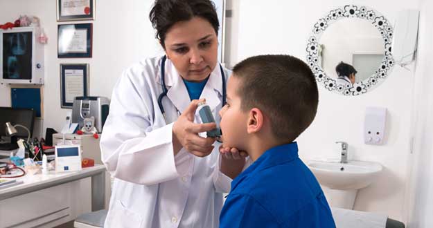 Una doctora aplica un broncodilatador a un niño con asma.