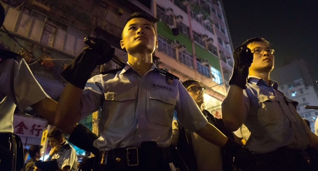 Policías armados con porras montan guardia en el barrio de Mong Kong (Hong Kong).