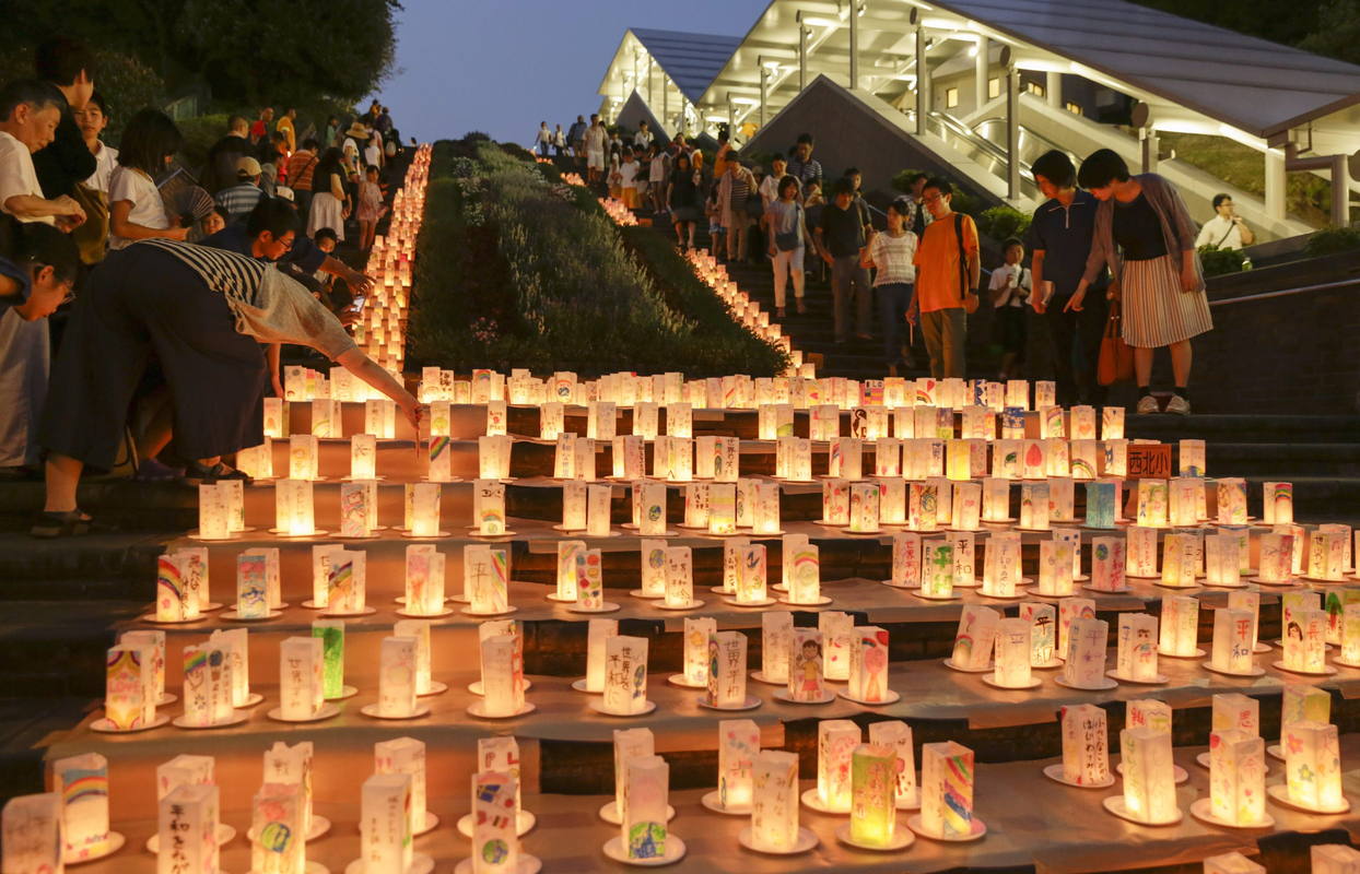 Locales y visitantes pasean por el camino de linternas de papel colocadas en el Parque de la Paz de Nagasaki.