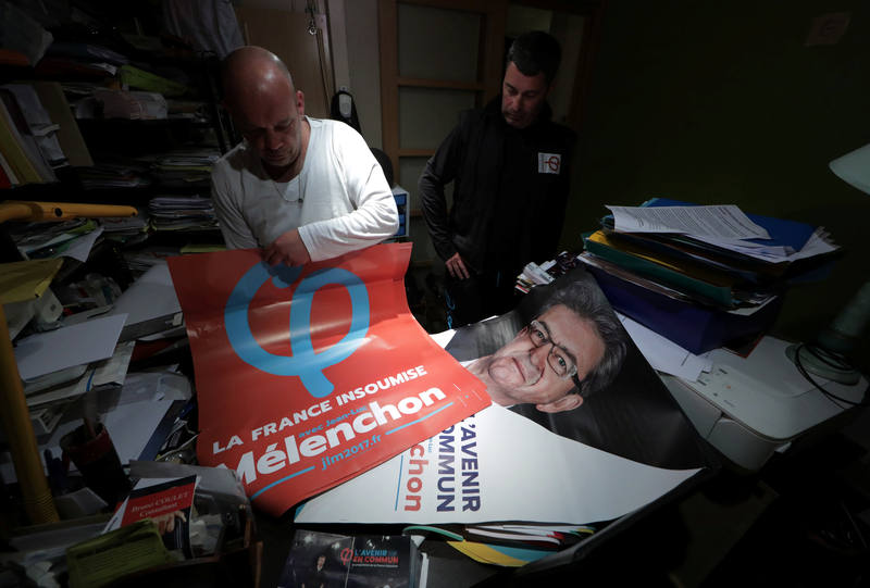 Un militante del Partido de Izquierda prepara varios carteles con la imagen del candidato, Jean-Luc Mélenchon