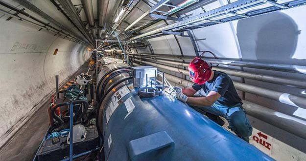 Un soldador trabajando con las interconexiones entre los dipolos magnéticos en el Gran Colisionador de Hadrones.