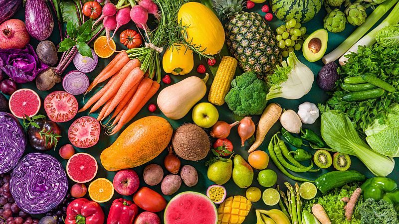Frutas y verduras frescas y coloridas sobre fondo verde, promoviendo una dieta saludable durante la menopausia.