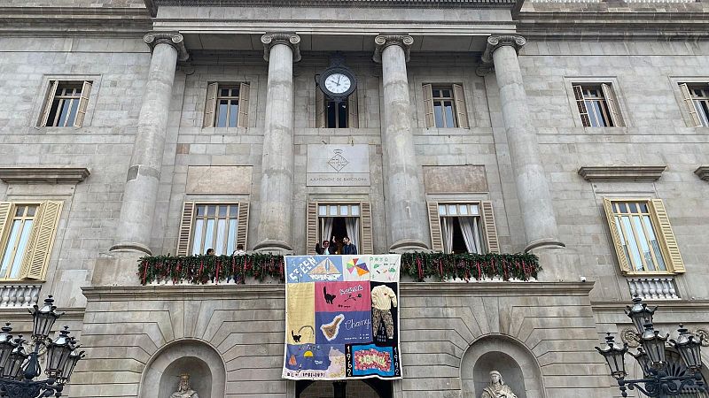 Dos tapissos i un llaç vermell en suport a la lluita contra el VIH