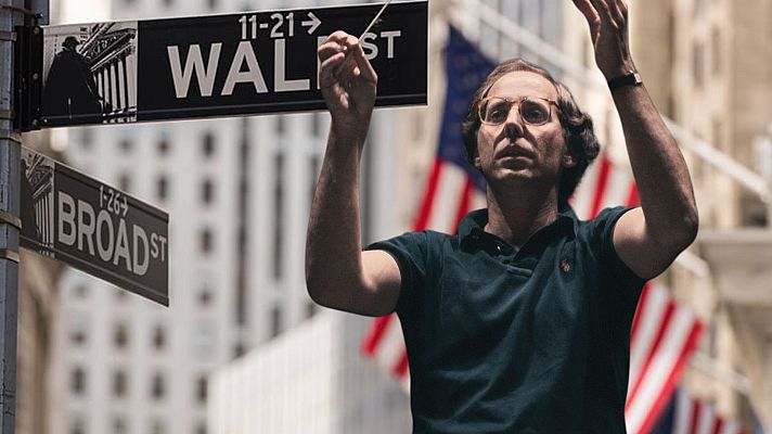 Gilbert Kaplan, con gafas y polo oscuro, dirige una orquesta imaginaria en Wall Street, Nueva York.  Imagen relacionada con Radio Clásica.