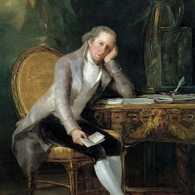 Retrato de Jovellanos pensativo, sentado en silla dorada con un papel en la mano. Lleva chaqueta clara y camisa blanca, ante un escritorio con plumas y papeles.