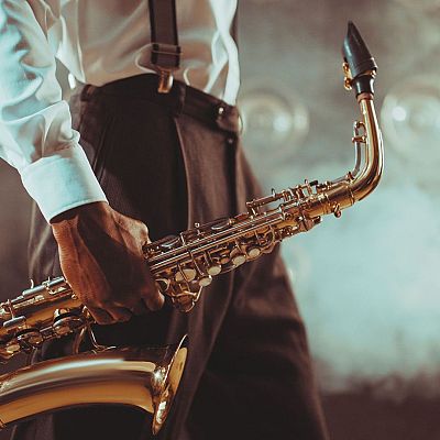 Saxofonista con camisa blanca y tirantes, sosteniendo un saxofón dorado en un ambiente de club de jazz. Ilustración para un programa de radio sobre música jazz.