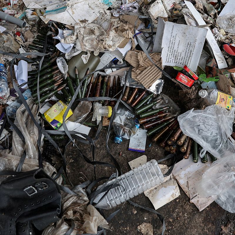 Restos de municiones y basura doméstica mezclados en una pila de escombros.  Indicios de un entorno afectado por la violencia.