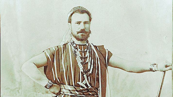 Retrato sepia de Julián Gayarre con atuendo teatral: túnica rayada, turbante, collares y brazaletes. Pose seria y firme.