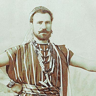 Retrato sepia de Julián Gayarre con atuendo teatral: túnica rayada, turbante, collares y brazaletes. Pose seria y firme.