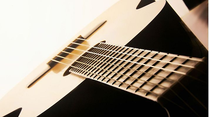 Guitarra acústica en primer plano, diagonal, fondo blanco.  Texto: 'Sinfonía de la mañana: Relato a la guitarra. La dársena'.