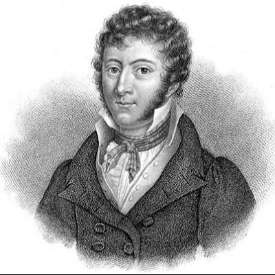 Retrato fotográfico en blanco y negro de un hombre con chaqueta oscura y camisa blanca, pelo corto y rizado.  Aspecto del siglo XIX.