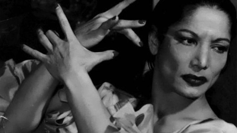 Primer plano en blanco y negro de Carmen Amaya, bailaora de flamenco, con mirada intensa y manos expresivas en movimiento.