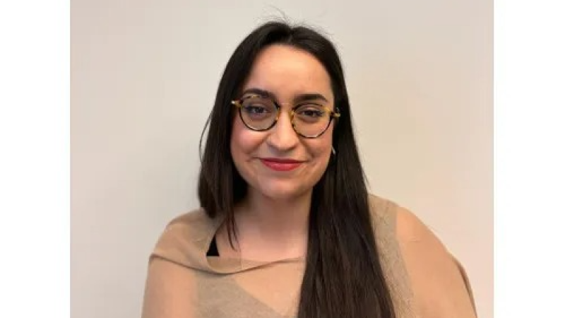 Retrato de Olympia Arango, periodista y presentadora, con gafas de montura redonda y labial rojo. Fondo liso y claro.