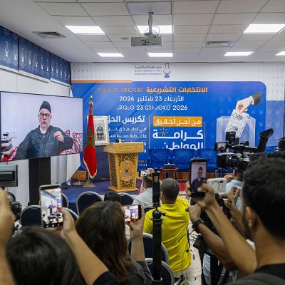 Evento político en Marruecos con banner de \"Elecciones Legislativas\" el \"23 de septiembre de 2026\" del \"Partido de la Justicia y el Desarrollo\" y proyección de Abdelilah Benkirane.