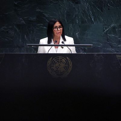 Delcy Rodríguez, Vicepresidenta Ejecutiva de Venezuela, habla en un evento de la ONU. Lleva chaqueta blanca, gafas y está detrás de un atril con el emblema de la ONU.