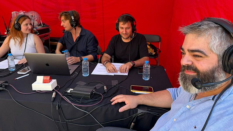 Cuatro personas con auriculares participan en una emisi�n de radio o grabaci�n, sentadas alrededor de una mesa con equipo t�cnico. Dami� Amor�s, a la derecha, sonr�e mientras los dem�s se concentran en sus tareas.
