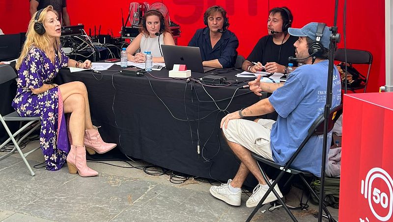 Cinco personas participan en una retransmisi�n de radio con micr�fonos y auriculares. Pilar Rahola destaca con su vestimenta morada y rosa. Un logo con "50" y un fondo rojo indican una celebraci�n.