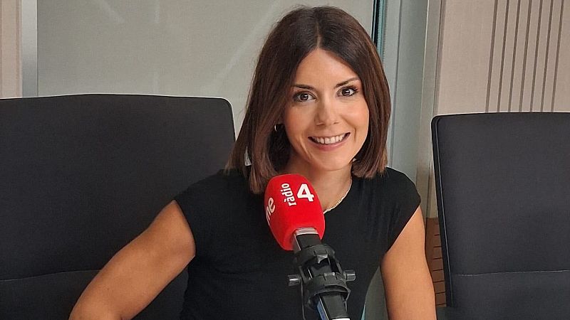 Anna Gurgu�, presentadora, sonr�e en un estudio de radio con un micr�fono "rne radio 4" rojo. Fondo luminoso con sillas oscuras.