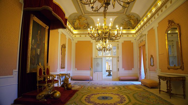 Interior suntuoso del Palacio de la Almudaina con mobiliario regio, retrato de figura militar y decoración clásica.