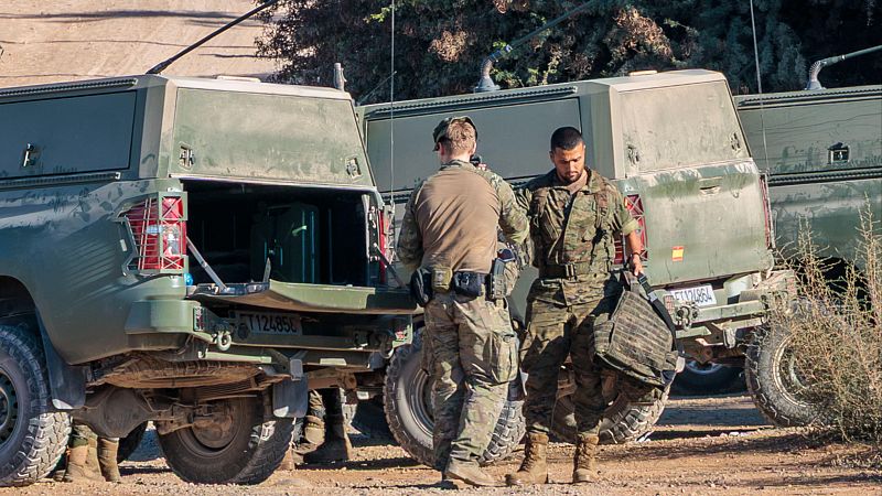Dos soldados del Ejército de Tierra español y dos vehículos militares tipo pick-up en un entorno árido y soleado. Matrículas "ET 12485C" y "ET 120864".