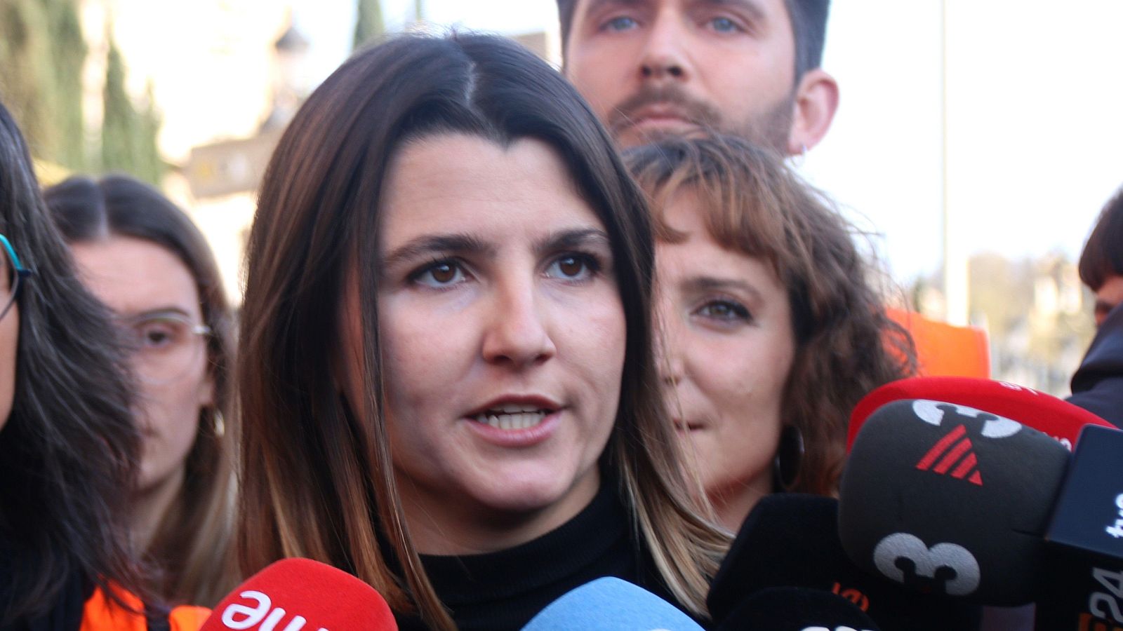 Carme Arcarazo, activista, habla ante micrófonos de RNE, TV3 y 24 Horas en un entorno exterior.