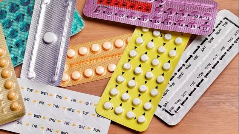 Diversos bl�steres de p�ldoras anticonceptivas femeninas con d�as de la semana y n�meros impresos, dispersos sobre madera.