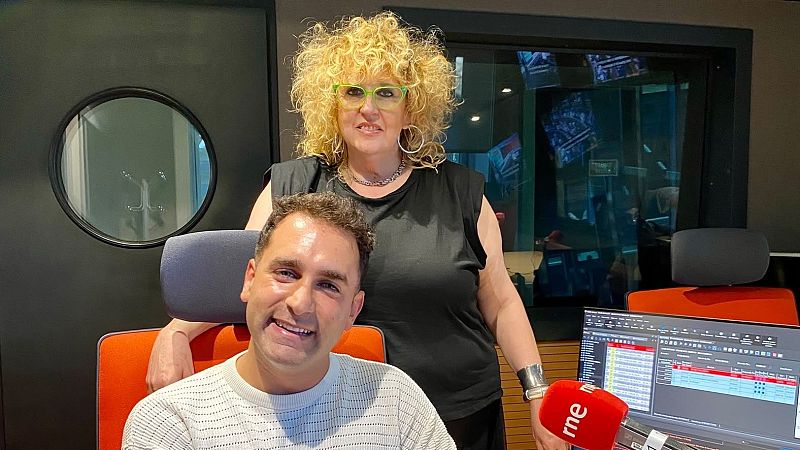 Manel Ferrer y una mujer sonr�en a c�mara en un estudio de radio. Se aprecian un micr�fono de RNE y un monitor con gr�ficos.