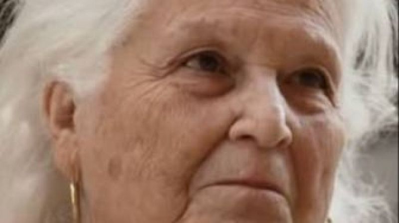 María Teresa Campos, de perfil, con cabello blanco y pendiente dorado. Expresión serena y pensativa, fondo desenfocado.