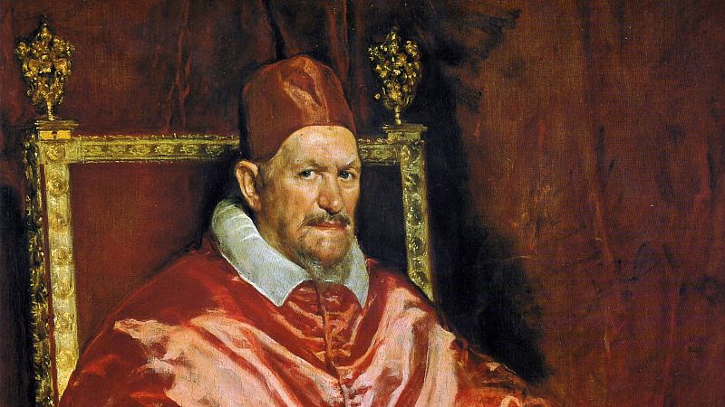 Retrato al �leo del Papa Inocencio X por Diego Vel�zquez. El pont�fice viste ropajes rojos y mira fijamente desde un sill�n dorado, con un fondo de cortina roja.