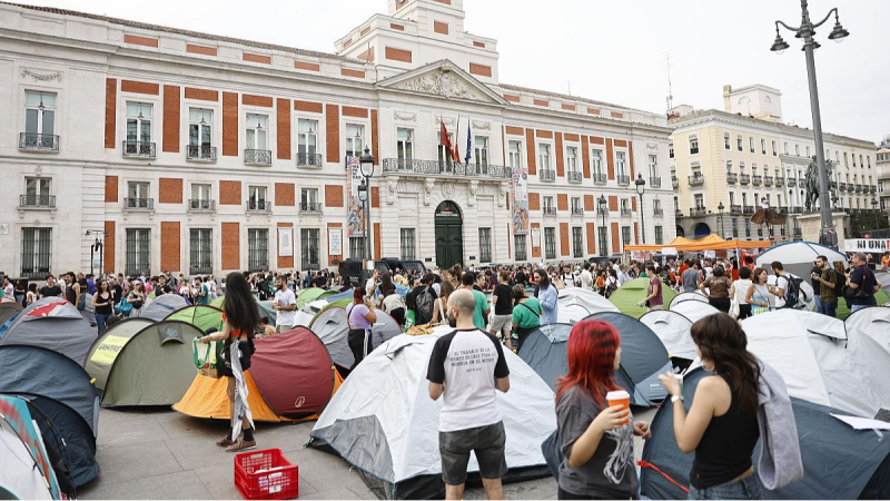 Acampada de protesta en la Puerta del Sol, Madrid. Multitud, tiendas de campa�a y un hombre con camiseta que dice "EL TRABAJO ES DE QUIEN LO HACE, NO DE QUIEN LO MANDA NI DE QUIEN LO ROBA".