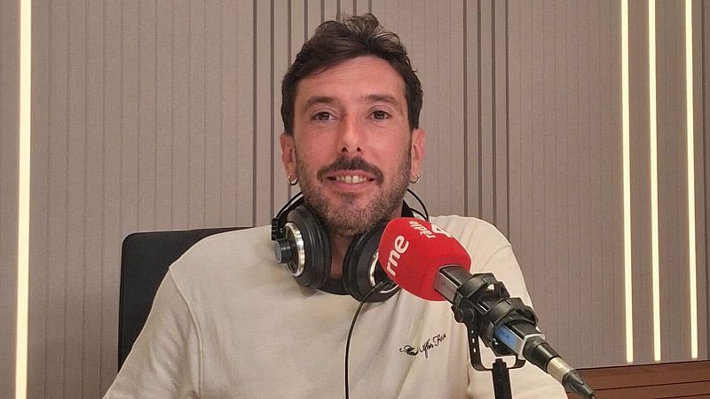 El periodista Marc Llibre sonr�e en un estudio de radio con auriculares al cuello y un micr�fono con espuma roja de "rne r�dio 4" en primer plano.