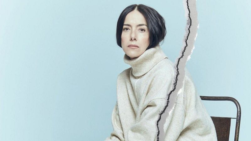 Retrato de medio cuerpo de la actriz Cecilia Suárez con jersey de cuello alto beige sobre fondo azul, con un efecto de rasgadura de papel vertical a la derecha.
