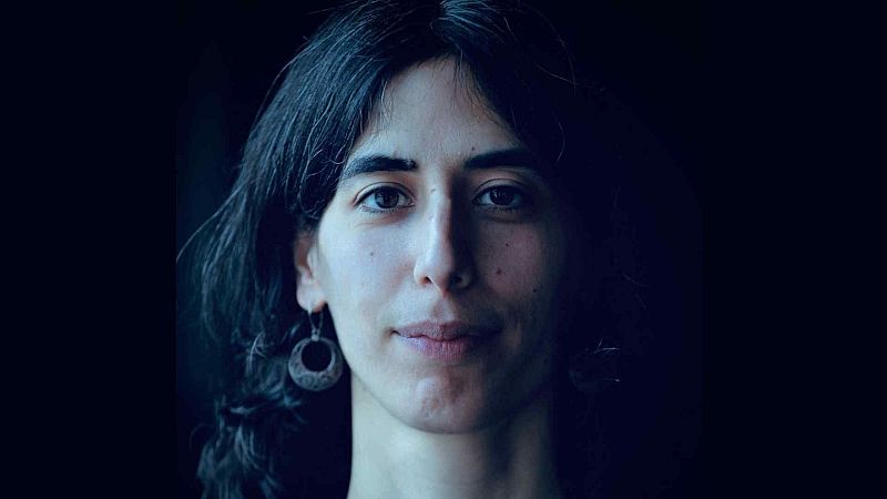 Retrato en primer plano de la compositora Nuria Gim�nez Comas con expresi�n serena y cabello oscuro sobre un fondo negro.