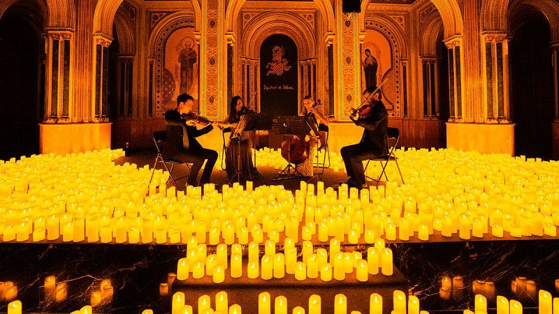 Un cuarteto de cuerda toca rodeado de cientos de velas en el Sal�n de Alfons el Magn�nim, bajo un arco con la inscripci�n 'Diputaci� de Val�ncia'.