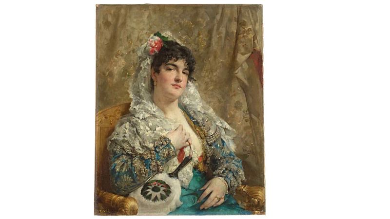 Pintura al �leo de una joven vestida de maja espa�ola con mantilla blanca y chaqueta azul bordada en oro, sentada en un sill�n dorado mientras sostiene un abanico.