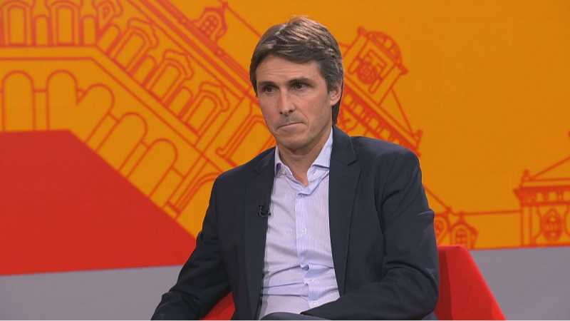 Salvador Verg�s, con americana azul y camisa clara, posa serio en el plat� de "El pla B" ante un fondo naranja con la silueta de un edificio.