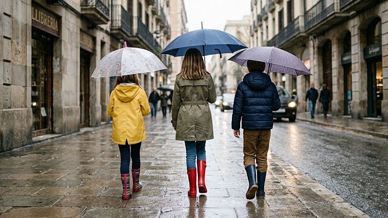 Tres ni�os con paraguas y botas de agua caminan de espaldas por una calle peatonal mojada frente a un comercio con un cartel que dice "LLIBRERIA".