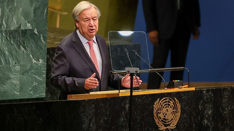 António Guterres, Secretario General de la ONU, gesticula durante un discurso en el podio oficial de la Asamblea General, vestido con traje oscuro y corbata rosa.