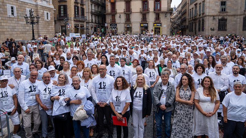 Salvador Illa posa junto a una multitud con camisetas blancas con el lema "1 OCT Dia Internacional de la Gent Gran" en la plaza de Sant Jaume de Barcelona.