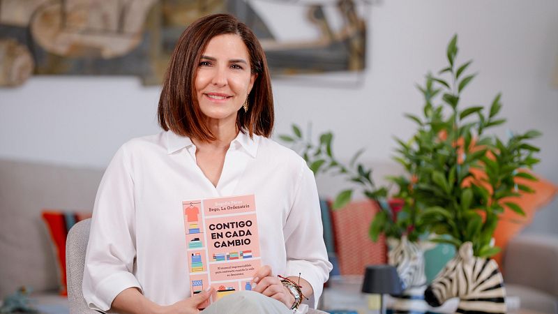 Bego�a P�rez, "La Ordenatriz", sonr�e sosteniendo su libro "Contigo en cada cambio" en un sal�n luminoso decorado con un sof� y una planta en un jarr�n de cebra.