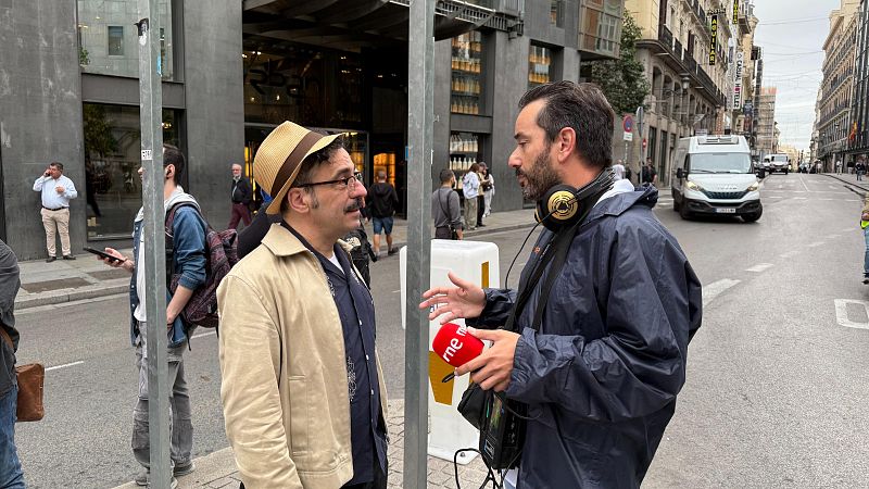 Darío Adanti es entrevistado en la calle por un reportero con micrófono de RNE en una avenida urbana.