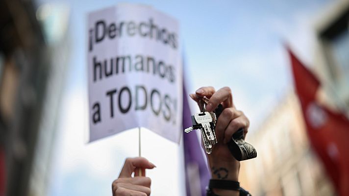 Una persona sostiene un juego de llaves durante una protesta por la vivienda frente al Congreso. En segundo plano, una pancarta reza \"derechos humanos a todos\"