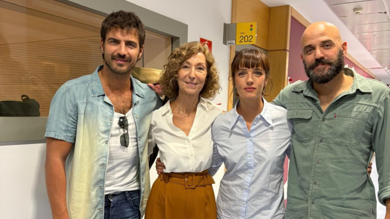 Cuatro personas posan sonrientes en un pasillo de una emisora de radio, mostrando una actitud cercana y amistosa.